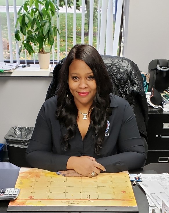 Woman sitting at a desk, smiling indoors.